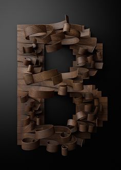 a wooden sculpture made out of strips of wood on a black background with the letter c in the middle