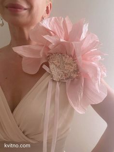 a woman wearing a pink flower brooch