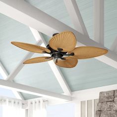 a ceiling fan mounted on the side of a wall in front of a stone fireplace