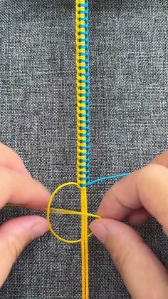 someone is stitching the end of a piece of fabric with yellow and blue thread