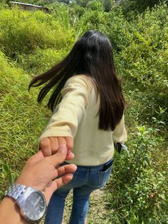 a person holding the hand of another person in front of some bushes and trees,