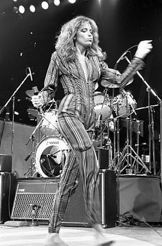 a woman standing on top of a stage in front of microphones