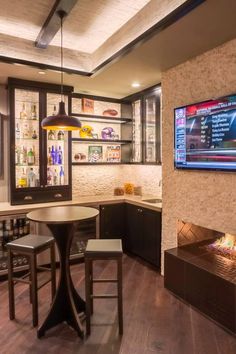 a television mounted to the wall in a kitchen next to a table with two chairs