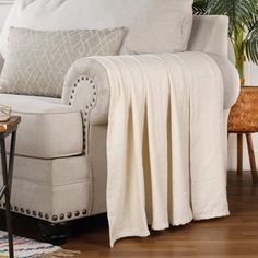 a living room with a couch, chair and side table covered by a white blanket