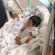 a small child laying in a crib next to stuffed animals