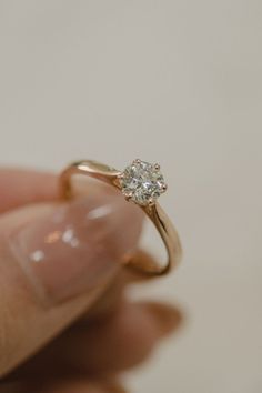 a woman's hand holding an engagement ring with a diamond