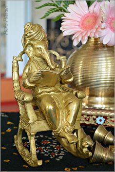 a gold statue sitting on top of a table next to a vase with flowers in it