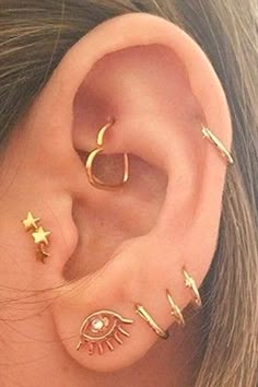 an ear with three different types of piercings on it's sides and two stars in the middle