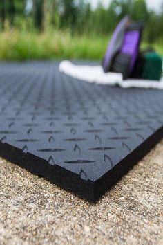 a piece of black plastic sitting on top of a cement floor next to a green and purple object