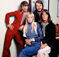 four people are posing for a photo in front of a piano