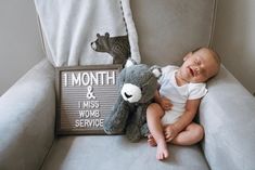 a baby laying on a couch next to a teddy bear and a sign that says i month