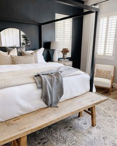 a bed with white sheets and pillows on top of it next to a wooden bench