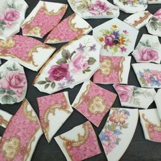 several pieces of pink and gold paper with flowers on them sitting on a black surface