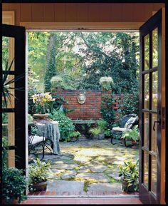 an open door leading to a patio with chairs and tables in the middle of it