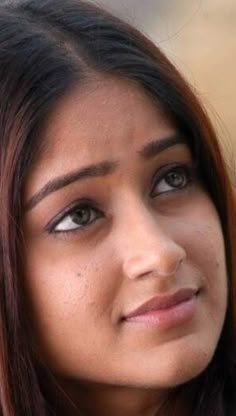 a close up of a woman with brown hair and blue eyes looking at the camera