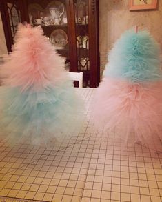 two blue and pink fluffy ball gowns sitting on top of a counter