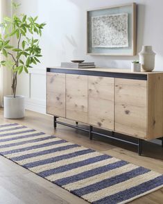 a large wooden cabinet sitting on top of a hard wood floor next to a potted plant