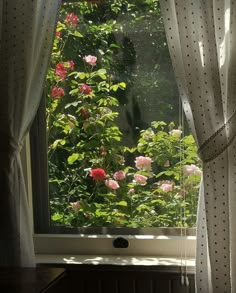 an open window with curtains and flowers in the foreground, looking out onto a lush green garden