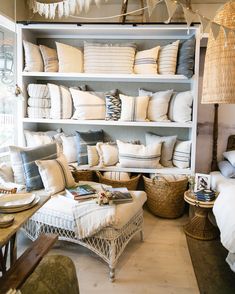 a living room filled with lots of white furniture and pillows on top of bookshelves