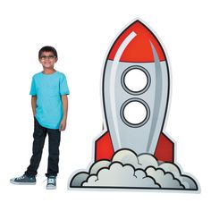 a young boy standing next to a cardboard rocket ship