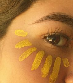 a woman's face with yellow painted on her cheek and eyeliners in the shape of bananas