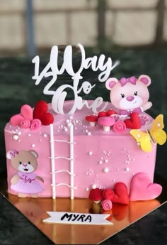 a pink cake with a teddy bear on top and flowers around the edges that says,'14 day to one '