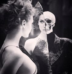 a woman looking at herself in the mirror with a skeleton mask on her head,