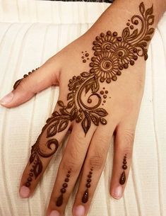 a henna tattoo on someone's hand that is decorated with flowers and leaves