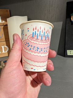 a hand holding up a cup with candles on it