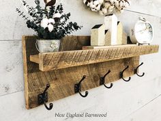 a wooden shelf with hooks on it and some flowers in a vase next to it