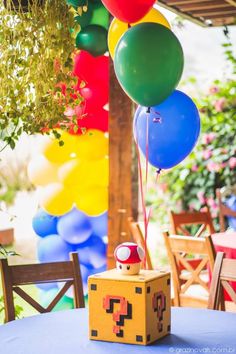 a box with balloons attached to it sitting on top of a table in front of some chairs