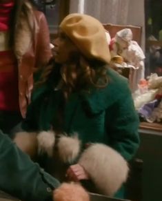 a woman in a green coat and hat talking to another woman