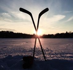 the sun is setting behind two skis in the snow with sticks sticking out of them