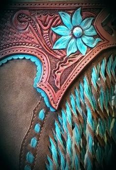 a close up view of a cowboy's tooled leather belt with blue flowers on it