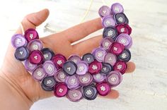 a hand holding a purple and black bracelet made out of buttoned up fabric pieces