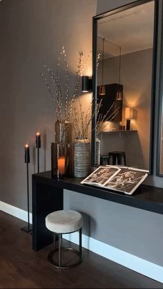 a table with candles, vases and pictures on it in front of a mirror