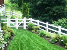 a white picket fence in the middle of a lush green yard