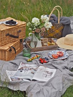 an open book on a blanket next to two wicker baskets filled with fruit and vegetables