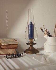 a blue candle is sitting on a table next to an open book and other items