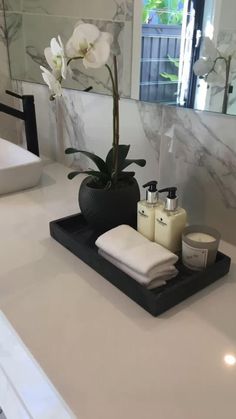 a bathroom counter with soaps, candles and flowers in the sink area on it