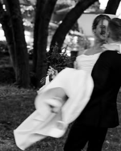 the bride and groom are walking through the park together, holding each other in their arms