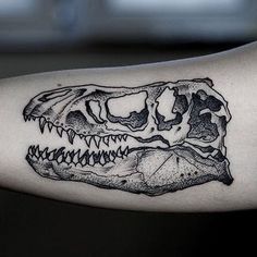 a black and white photo of a dinosaur's skull tattoo on the left arm