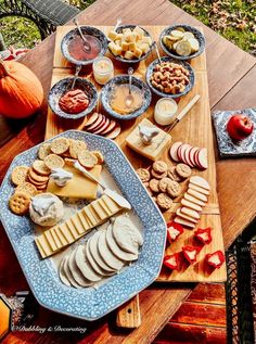 a wooden table topped with lots of cheeses and crackers on top of it