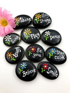 six black rocks with painted flowers and words on them that say, be you smile