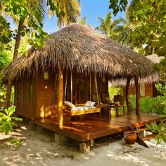 a small hut with a thatched roof and wooden deck in the middle of trees