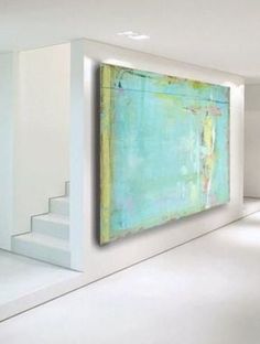 a large painting hanging on the wall in a room with white walls and flooring