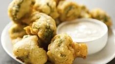 some fried food on a white plate with dipping sauce