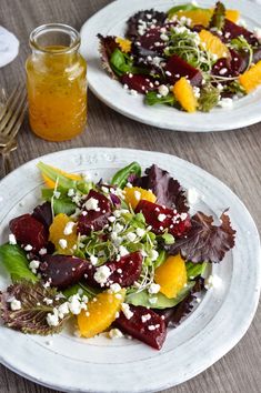 two white plates topped with salad on top of a wooden table