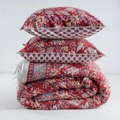 three pillows stacked on top of each other in different colors and patterns, with the covers folded down