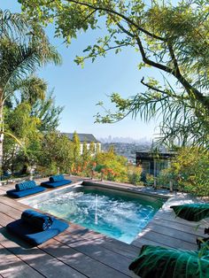 an outdoor swimming pool with lounge chairs and trees in the back ground, surrounded by greenery